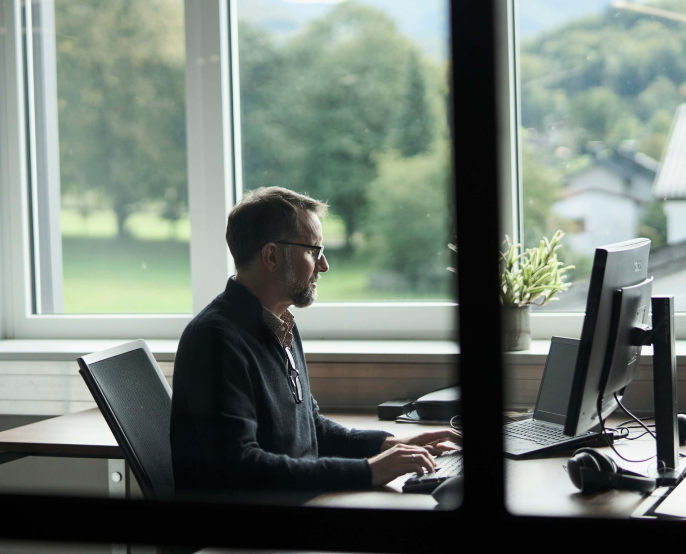 Ein junger Mann sitzt an seinem Arbeitsplatz und arbeitet am Computer