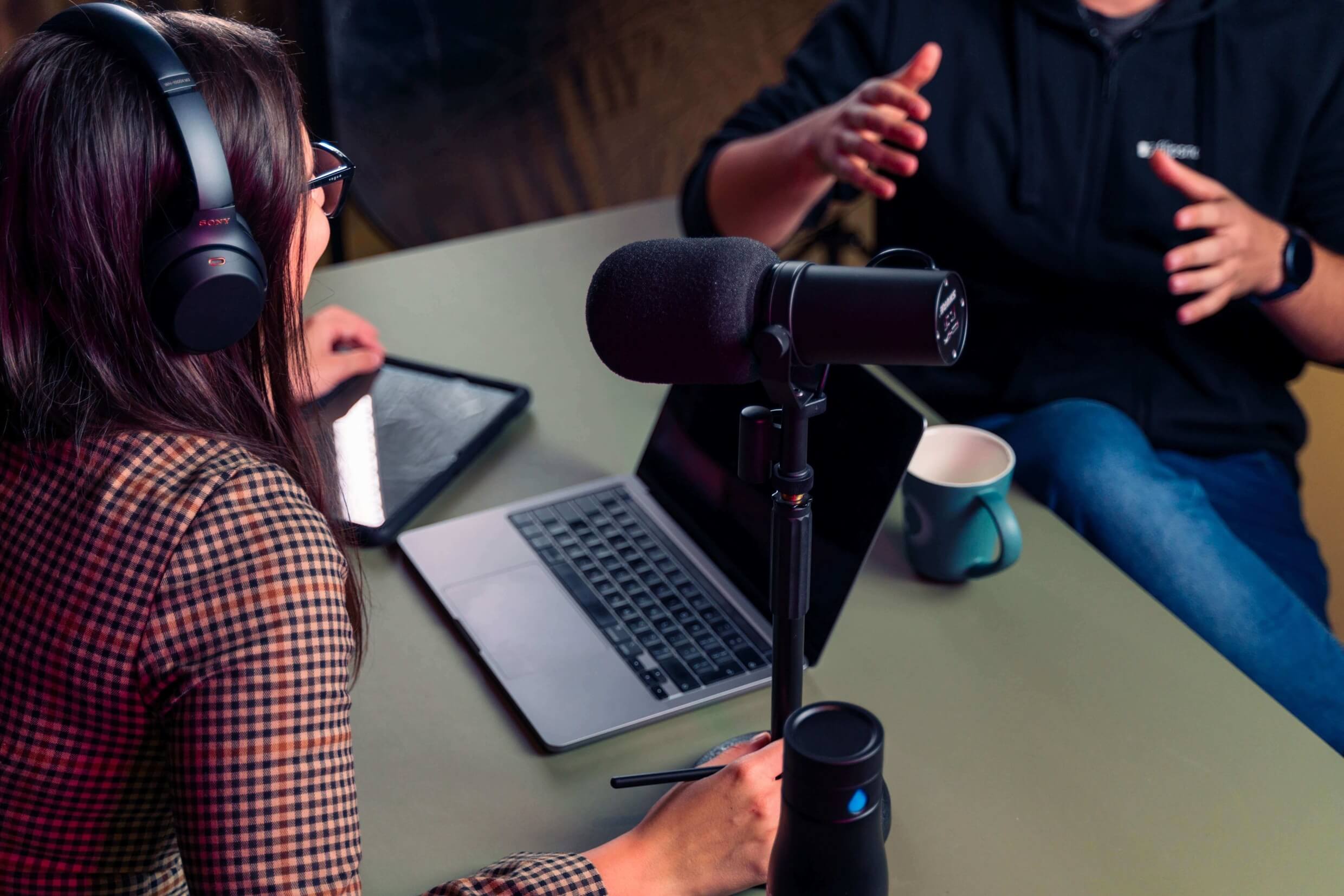 Eine Frau und ein Mann sitzen an einem Tisch während eines Podcasts